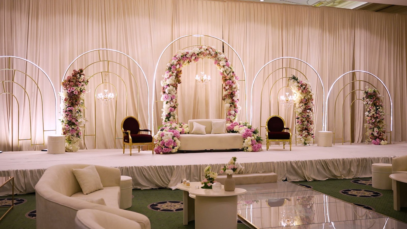 Wedding stage dressed with floral arches and a mirrored aisle, shot for a banquet hall in Al Khobar