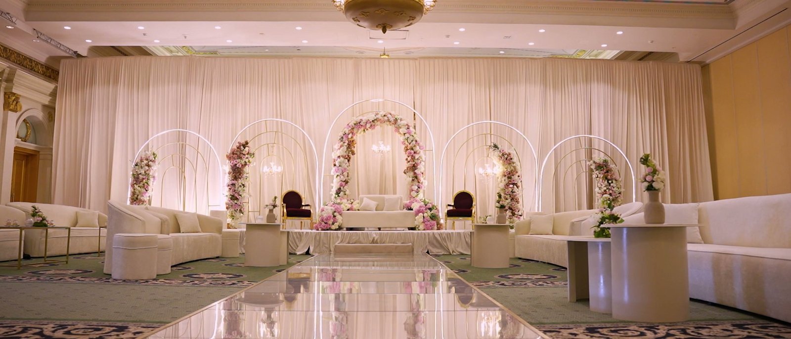 Wide view of a banquet hall walkthrough, mirrored floor and arched stage